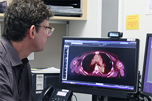 A man examines a medical image on a computer screen