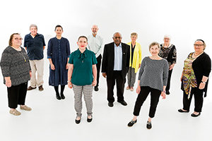 Nine members of the Consumer Advisory Council standing in a semi circular formation around a banner that reads 'Consumer Advisory Council – a voice for patients at Fiona Stanley Hospital'