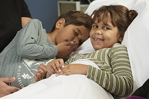 A young Aboriginal girl in a hospital bed with a young Aboriginal boy next to her
