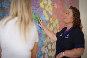 A female nurse looks at an art collage on a wall