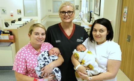 A midwife with two mothers holding their babies